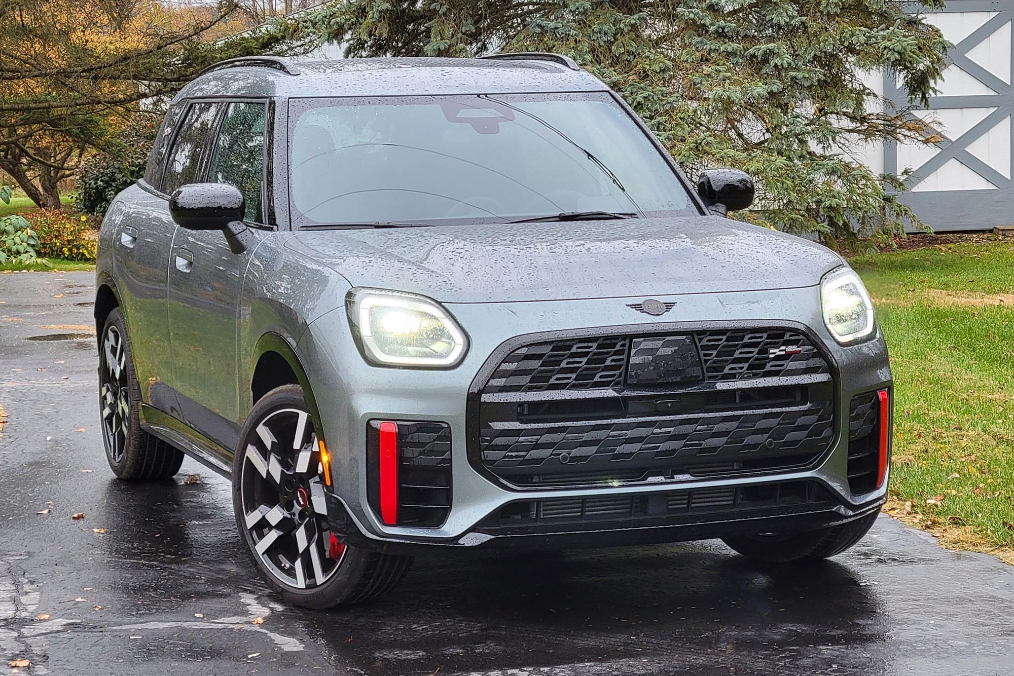 2025 Mini Countryman John Cooper Works in Smokey Green with grass, trees, and a shed in the background.