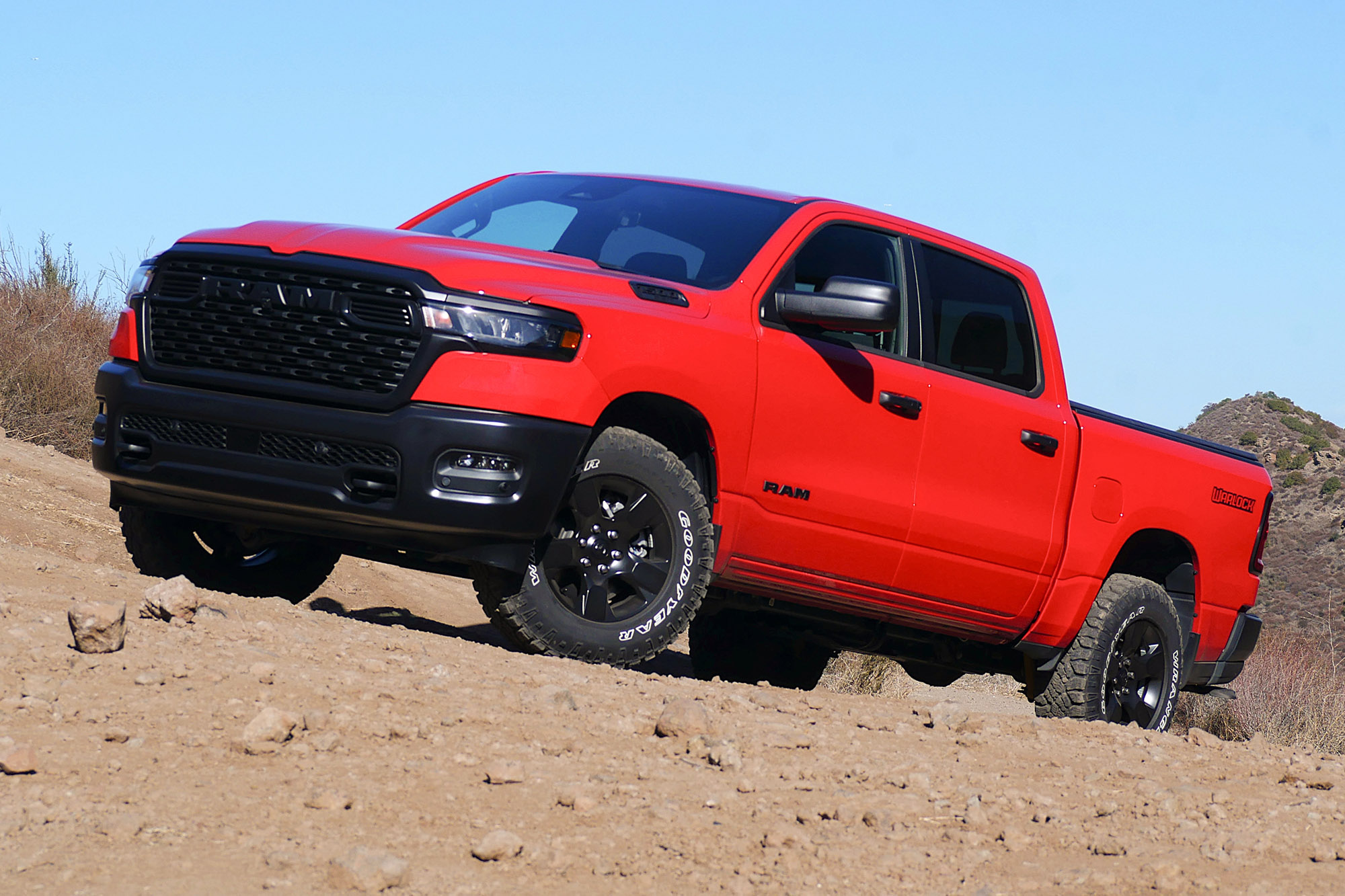 2025 Ram 1500 Warlock in Flame Red with mountains and blue sky in the background.