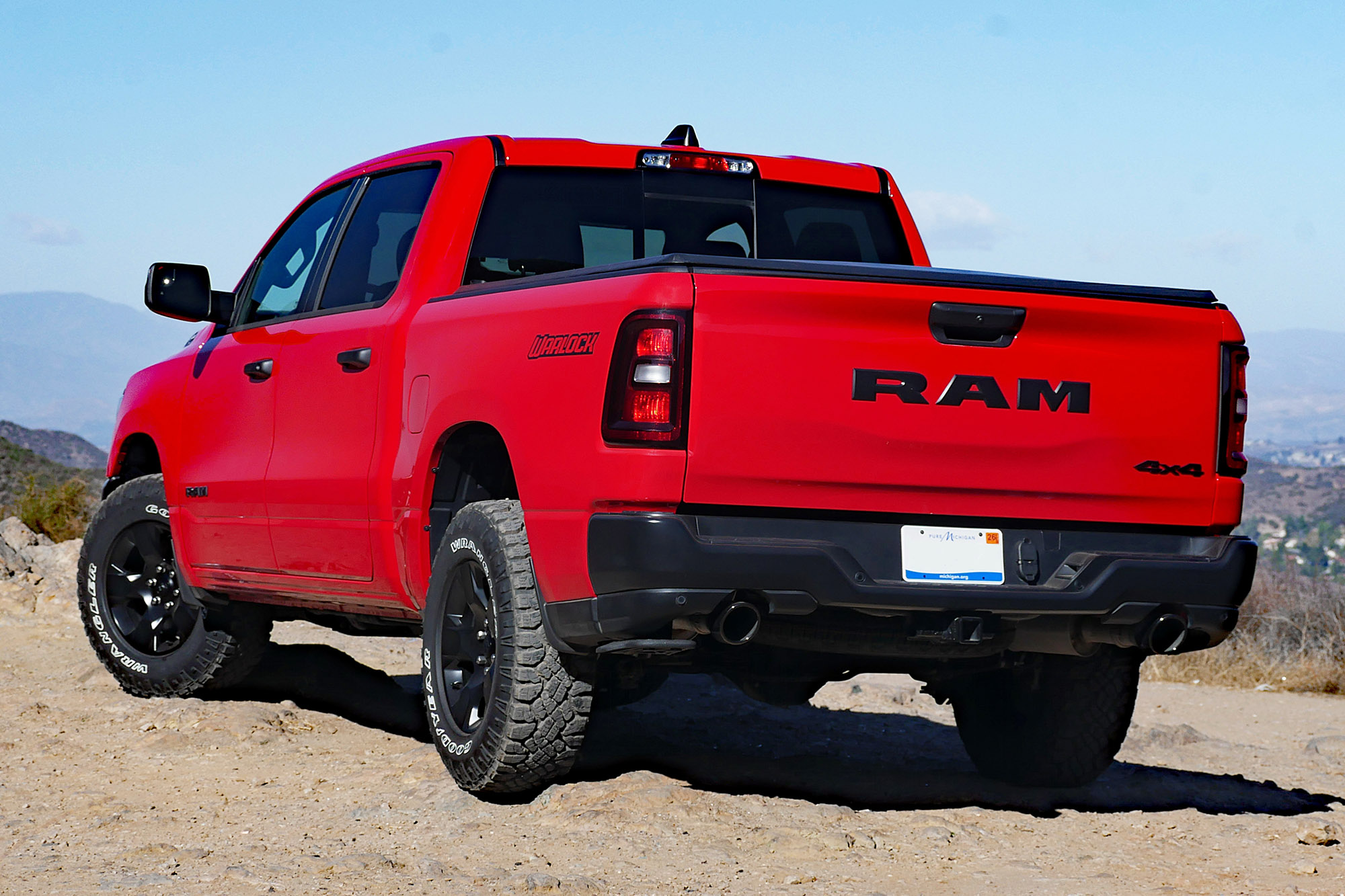 2025 Ram 1500 Warlock in Flame Red with mountains and blue sky in the background.