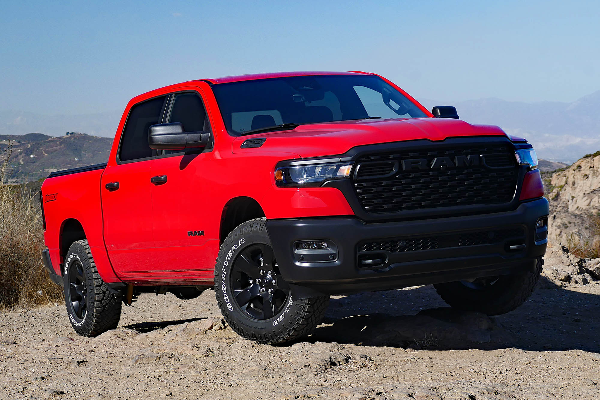 2025 Ram 1500 Warlock in Flame Red with mountains and blue sky in the background.