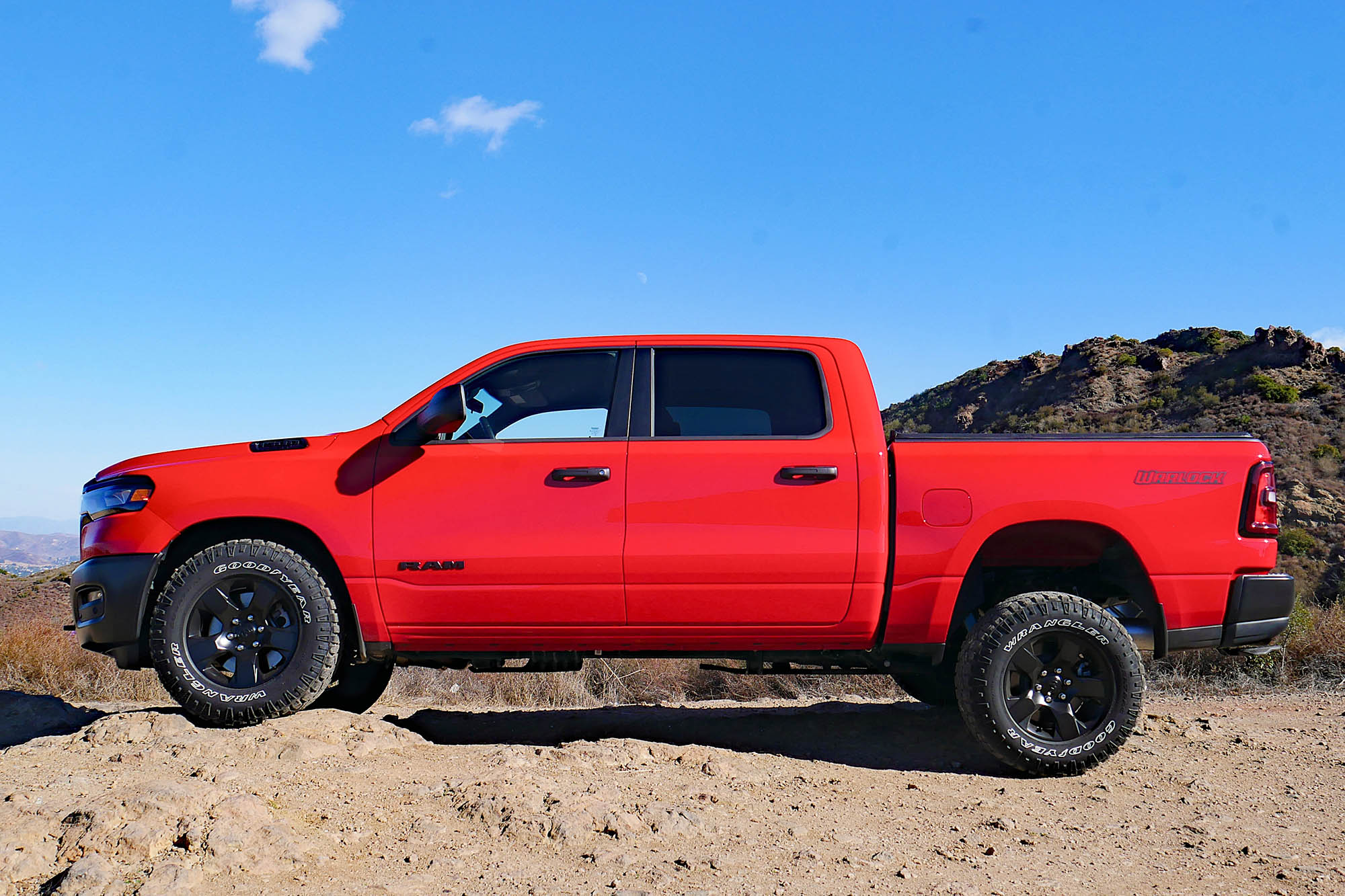 2025 Ram 1500 Warlock in Flame Red with mountains and blue sky in the background.