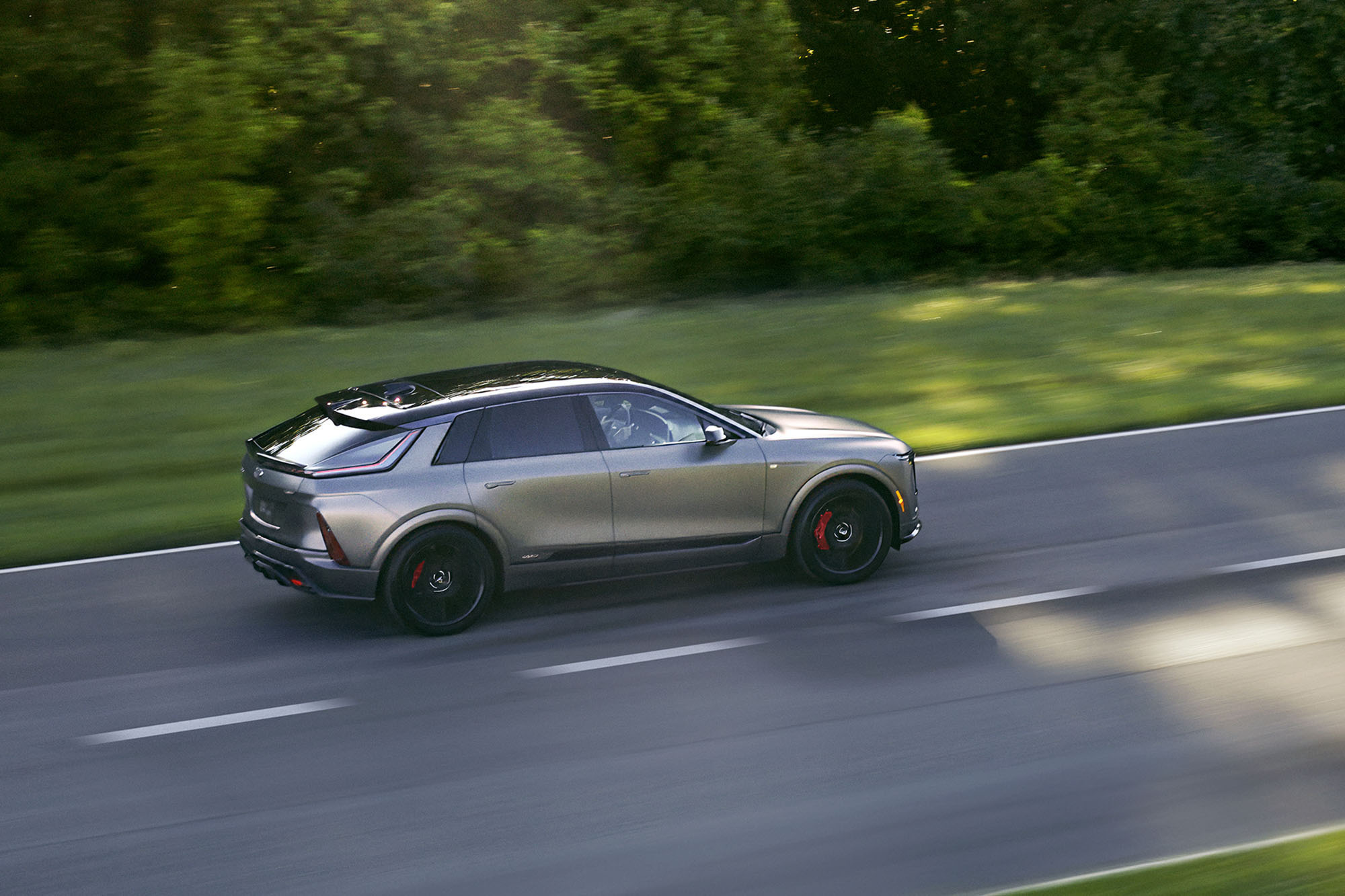 A right-side view of a gray 2025 Cadillac Lyriq-V driving on a highway.