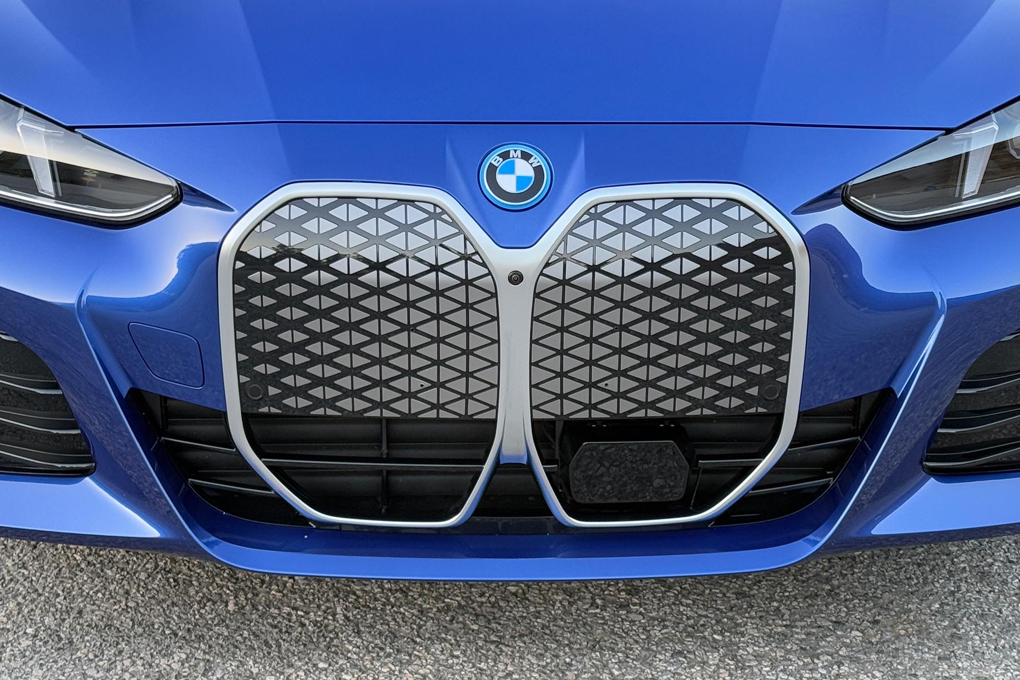 2025 BMW i4 eDrive40 in Portimao Blue showing the grille, BMW badge, and part of the headlights.