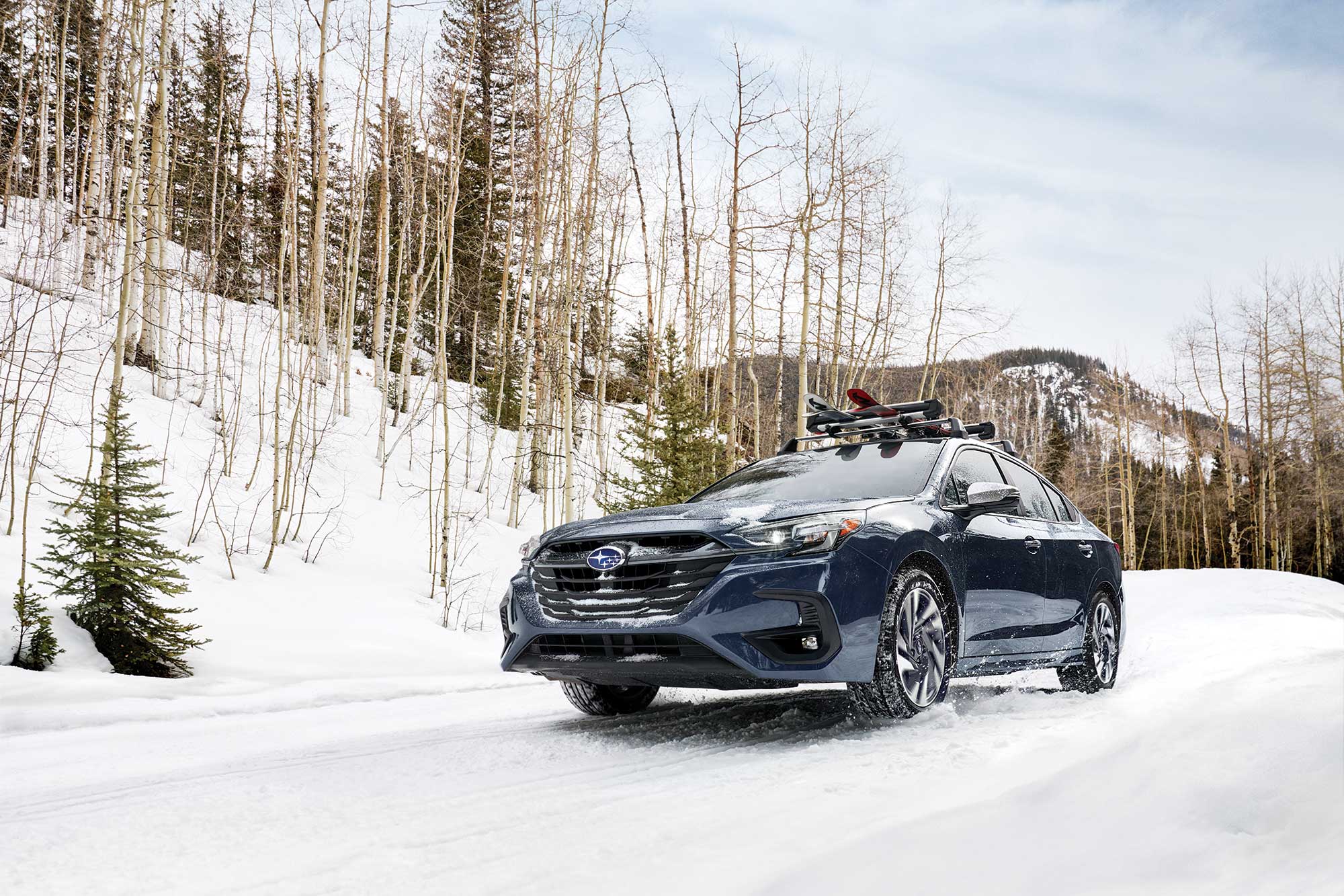 2024 Subaru Legacy in dark blue driving down a snowy hill