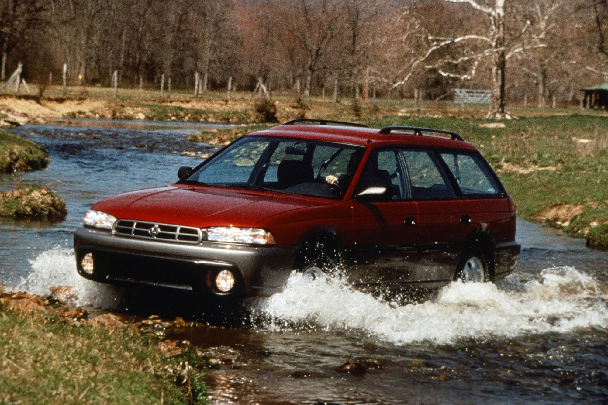 1996 Subaru Outback in dark red driving through a creek