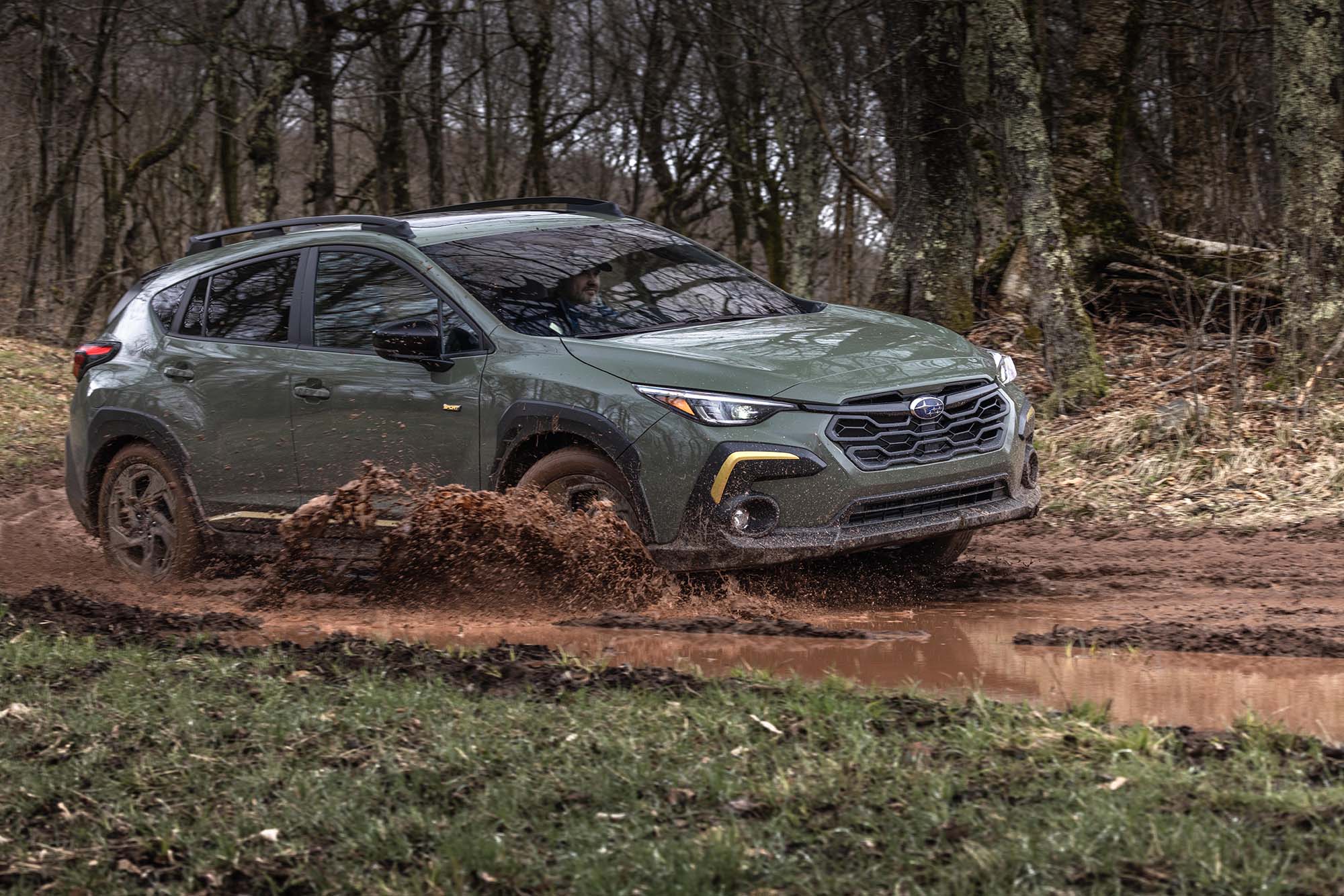 2024 Subaru Crosstrek in dark green driving through muddy water